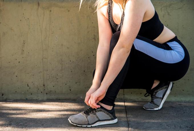 Mujer joven atandose los cordones de sus zapatillas deportivas